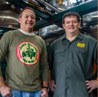 Ben and Daron Gruner standing with hands on hips and smiling, one wearing a shirt with the Gruner Brothers logo on it